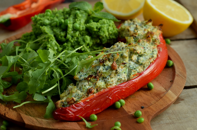 Zijaanzicht een houten bord met Zoete paprika's met ricottabroccolivulling en erwtenpuree