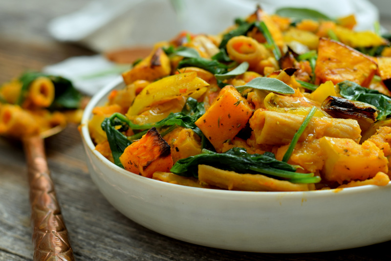 Zijaanzicht: rechts een wit bord met tortiglioni met butternutsaus link een lepel