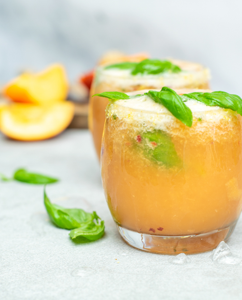 Fizzy nectarinemocktail. Twee lage, bolle glazen met een perzikkleurig, schuimend aperitief.