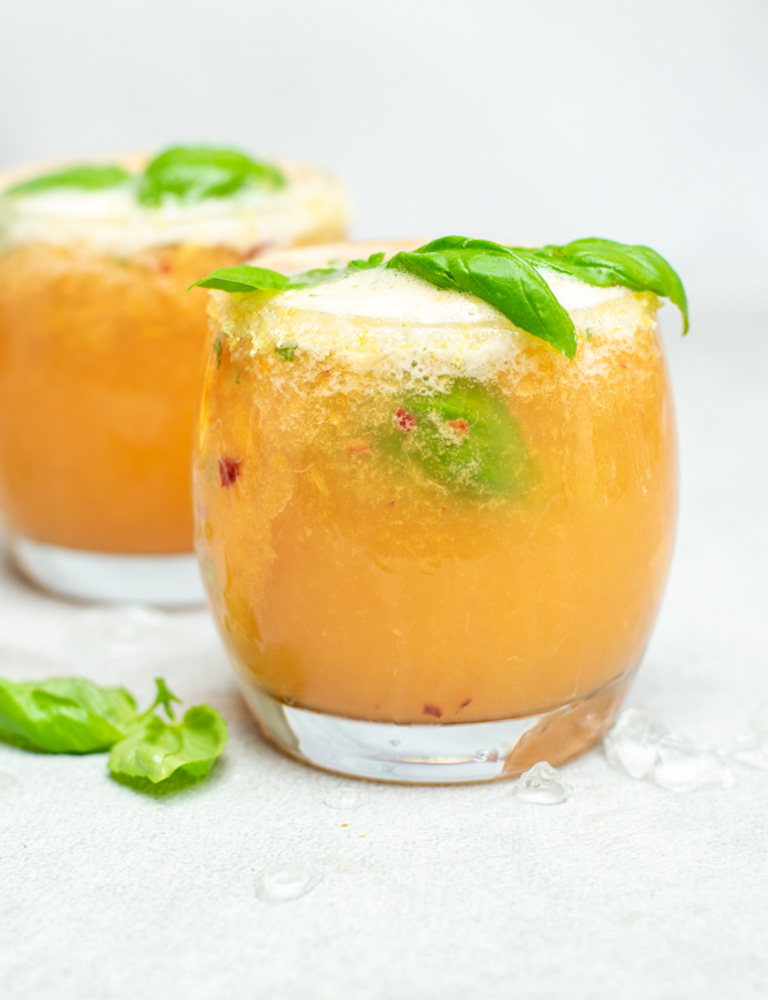 Fizzy nectarinemocktail. Twee lage, bolle glazen met een perzikkleurig, schuimend aperitief.